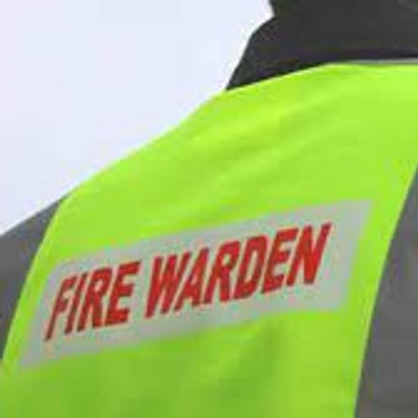 Man wearing a yellow reflective jacket, with fire warden printed on the back.