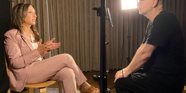 Two people engaged in a seated interview with professional lighting.