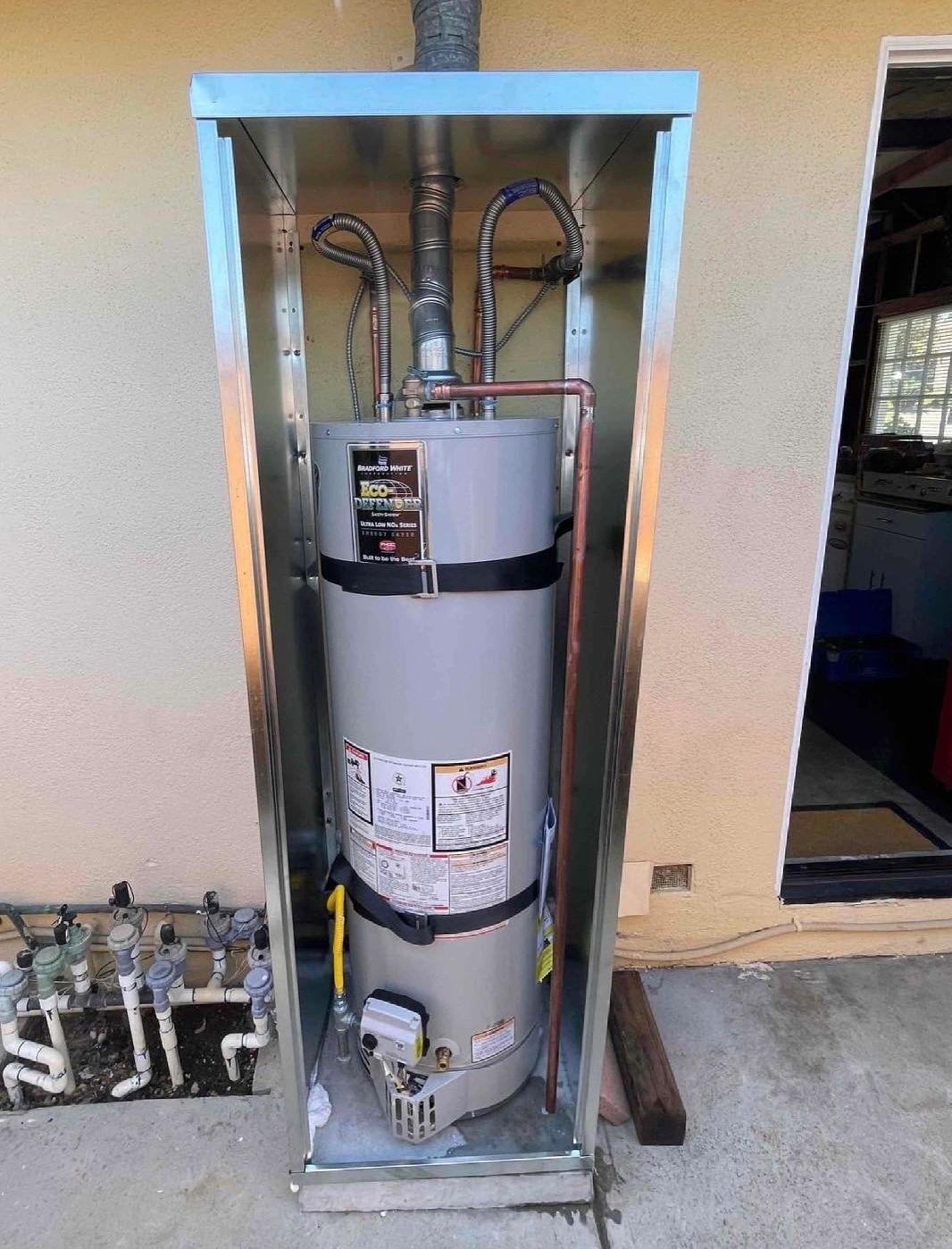 A modern water heater installed in an outdoor metal enclosure.