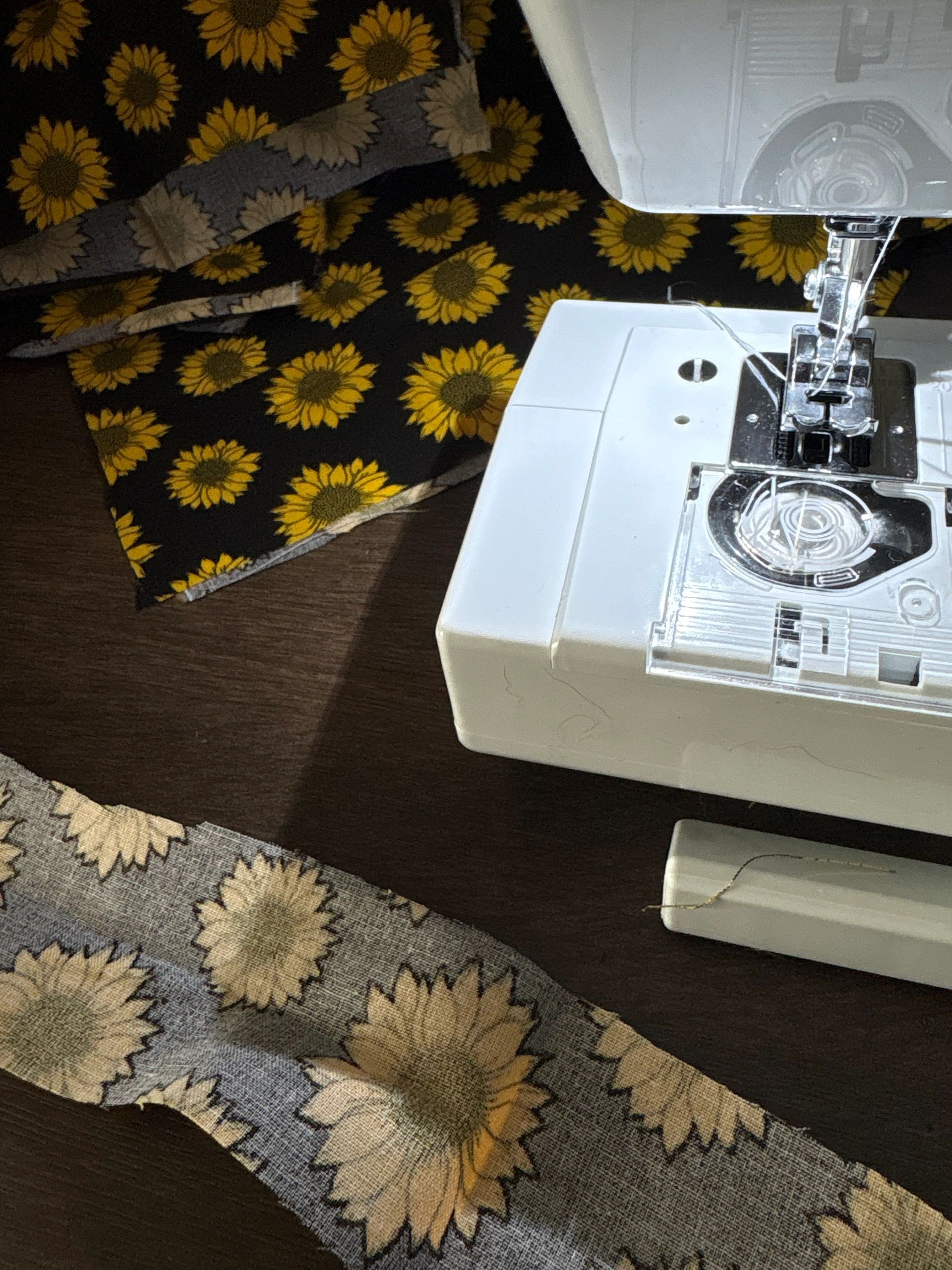 Sewing machine with sunflower-patterned fabric on a dark table.