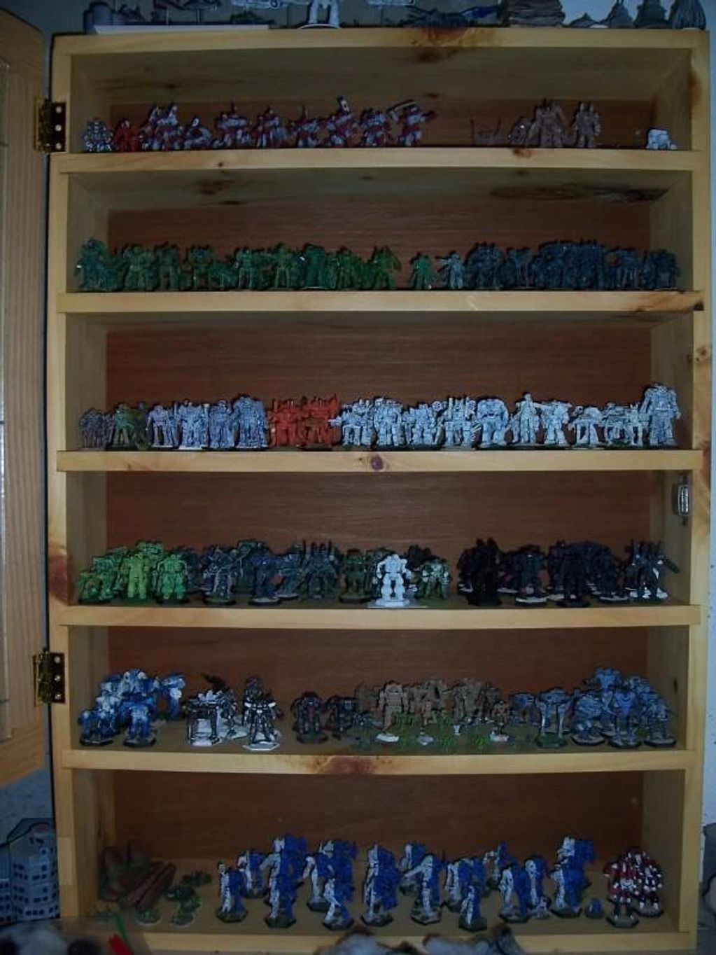 Wooden shelf filled with multiple rows of miniature painted figurines.