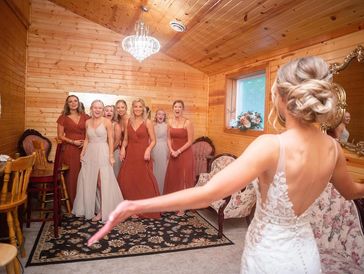 Bride in white gown with bridesmaids in red dresses in a dressing room.
