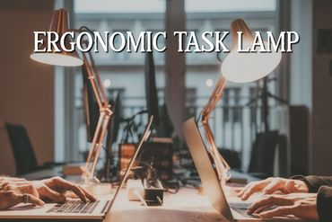 Two ergonomic task lamps illuminate a shared workspace with laptops.