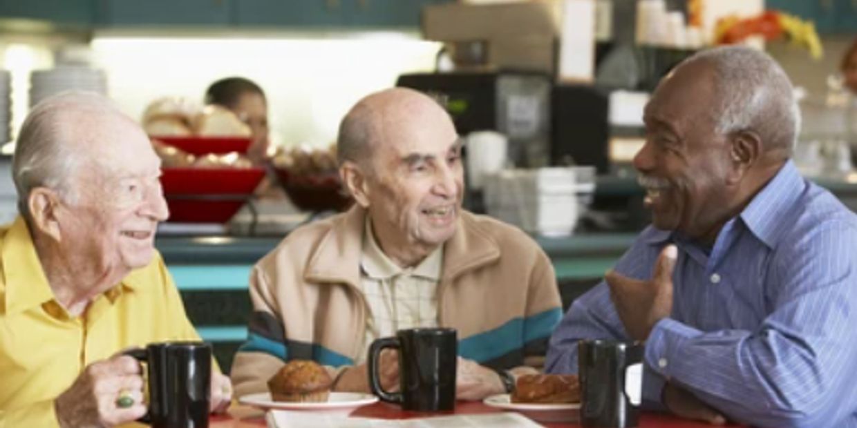 Three elderly men enjoying coffee and conversation.