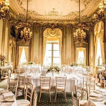 Elegant dining room with gold decor and round tables set for a formal event.