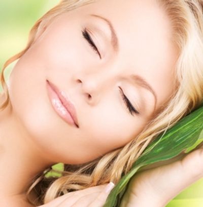 Woman with healthy skin leaning on leaf