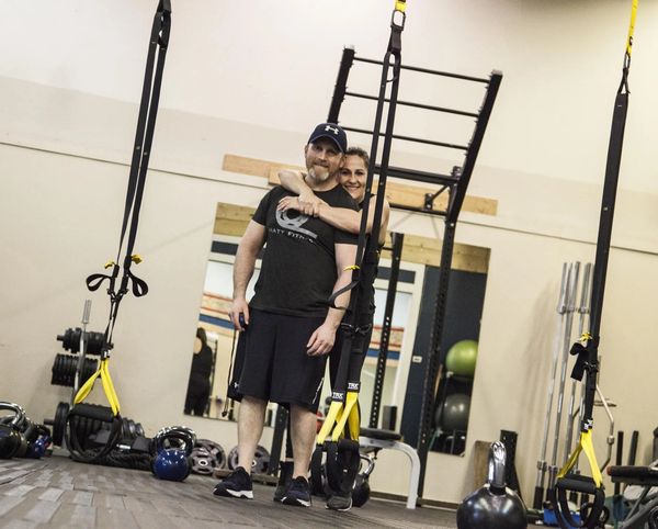 Trainer assisting man with weights.