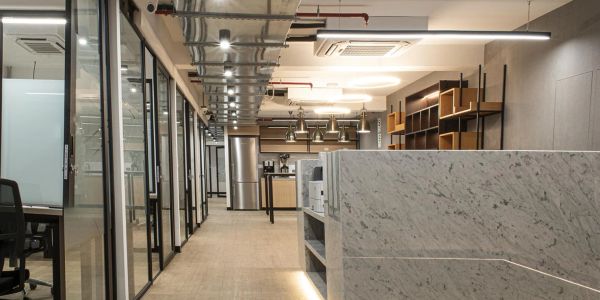 Modern office hallway with glass doors and marble countertops.