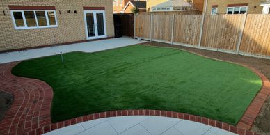 Fully landscaped garden in ipswich with artificial grass, clay pavers and porcleian patio.