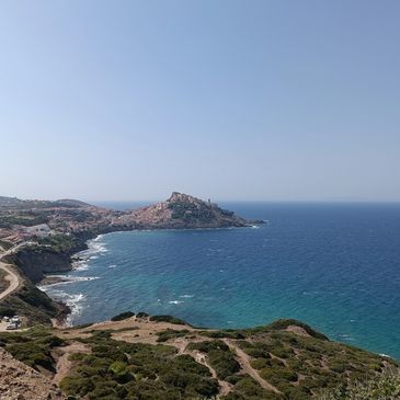 Küstenlandschaft mit blauem Meer und einer Stadt auf einer Landzunge.
