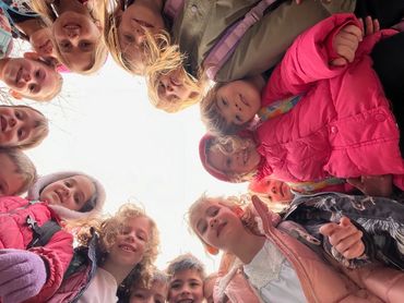 Children in a circle looking down at camera