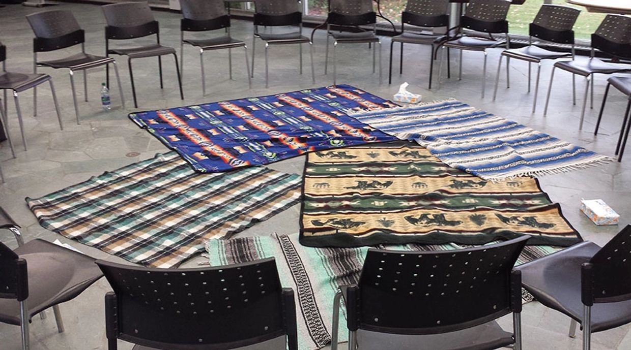 Blankets represent the lands of Canda, and chairs are in a circle for sharing and healing.