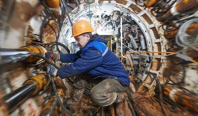 Worker in protective gear operating machinery inside a confined industrial space.