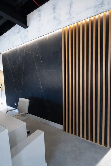 Feature wall upgrade using large-format porcelain tile and wood slat paneling.