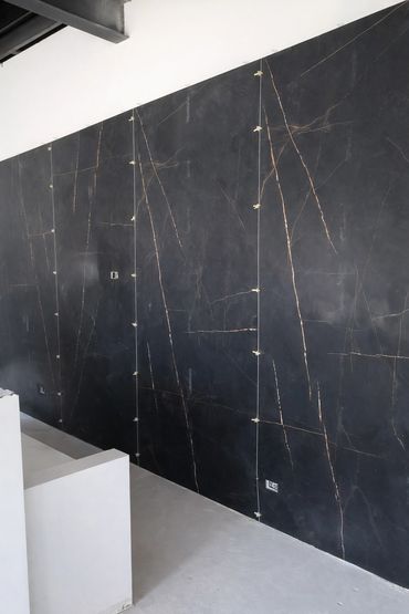 Large-format tile installation for feature wall with precise seams and wood panel detailing.