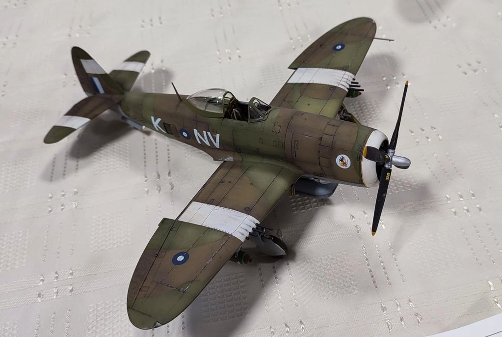 Model of a WWII fighter plane with camouflage and white stripes.