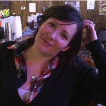 Woman with short dark hair smiling indoors.