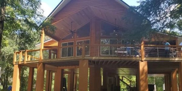 Wooden cabin with elevated deck in forest.