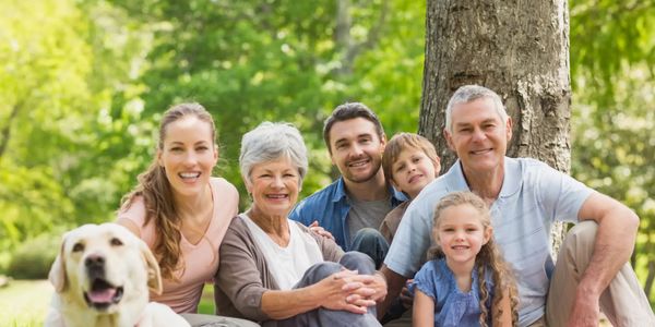 Happy multi-generational family enjoying a picnic outdoors with their dog.