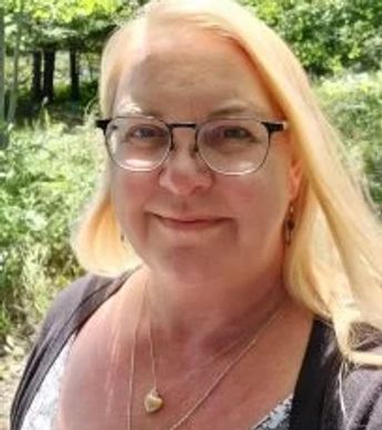 Smiling woman with glasses outdoors.