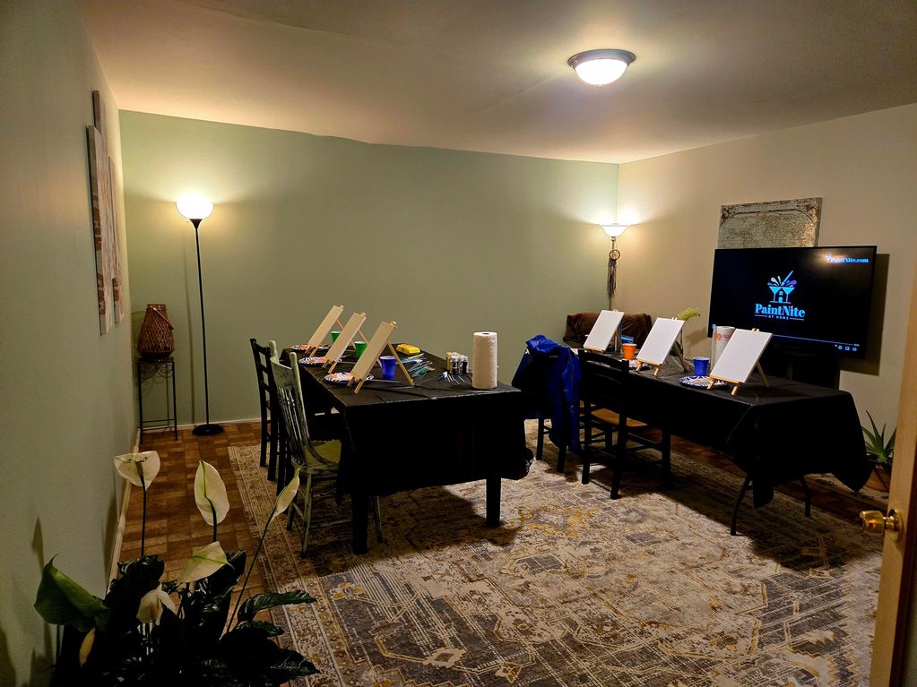Room set up for a group painting session with easels and art supplies.