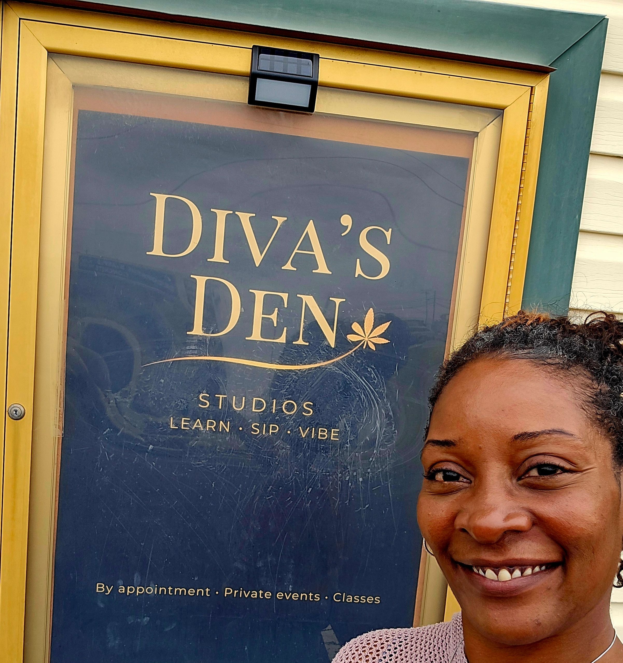 A smiling woman in front of a Diva's Den sign.