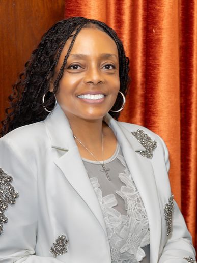 Smiling woman in white jacket with decorative beads.