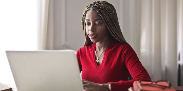 Woman in red working on a laptop.