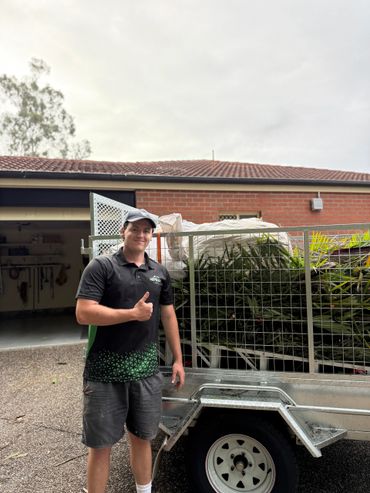 Man giving thumbs up next to a trailer loaded with garden waste.