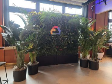 Faux boxwood hedge, with faux plants and custom corporate logo. Live plants on either side of photo