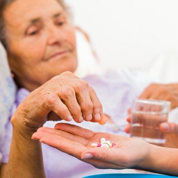 Elderly woman receiving medication with water assistance.