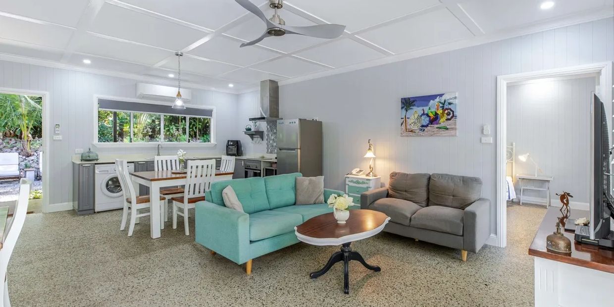 Bright modern living room and kitchen with gray and turquoise sofas.
