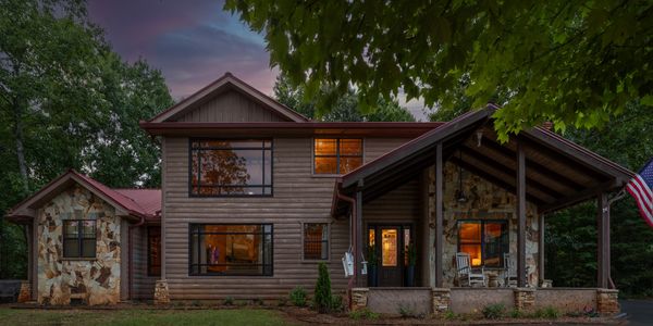Cozy two-story house (Monarch's Roost) at dusk with warm interior lights.