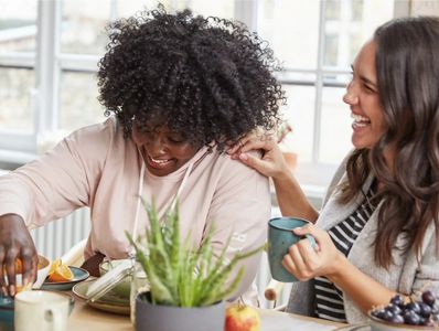 Two women who struggle with emotional eating and weight loss enjoying each other and healthy snacks.