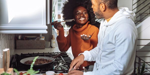 A happy couple cooking a healthy meal from their customized weight loss plan. 