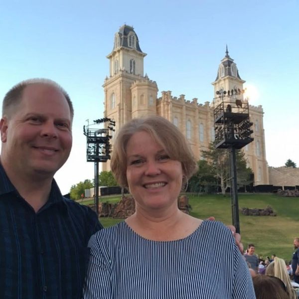Smiling couple posing in front of a historic building on a clear day.