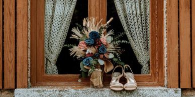 Bouquet and shoes on a rustic window ledge with lace curtains.