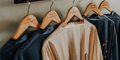 Bridal party robes hanging on personalized wooden hangers.