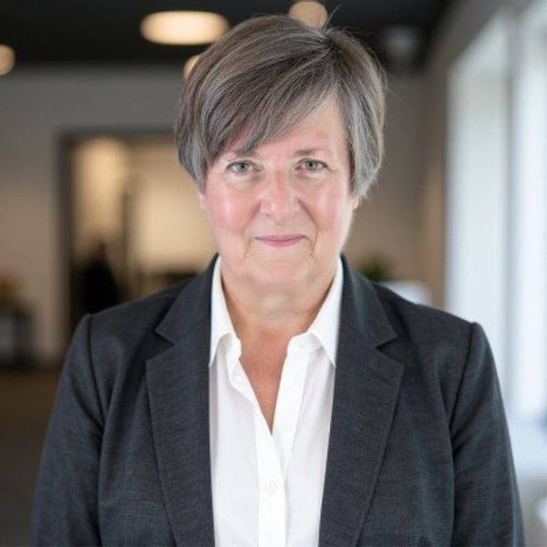 Professional woman in business attire smiling confidently indoors.