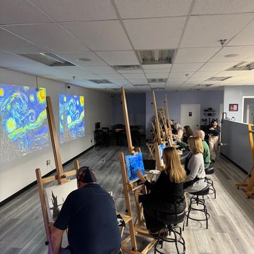 People painting in a studio with Van Gogh's Starry Night projected on the wall.