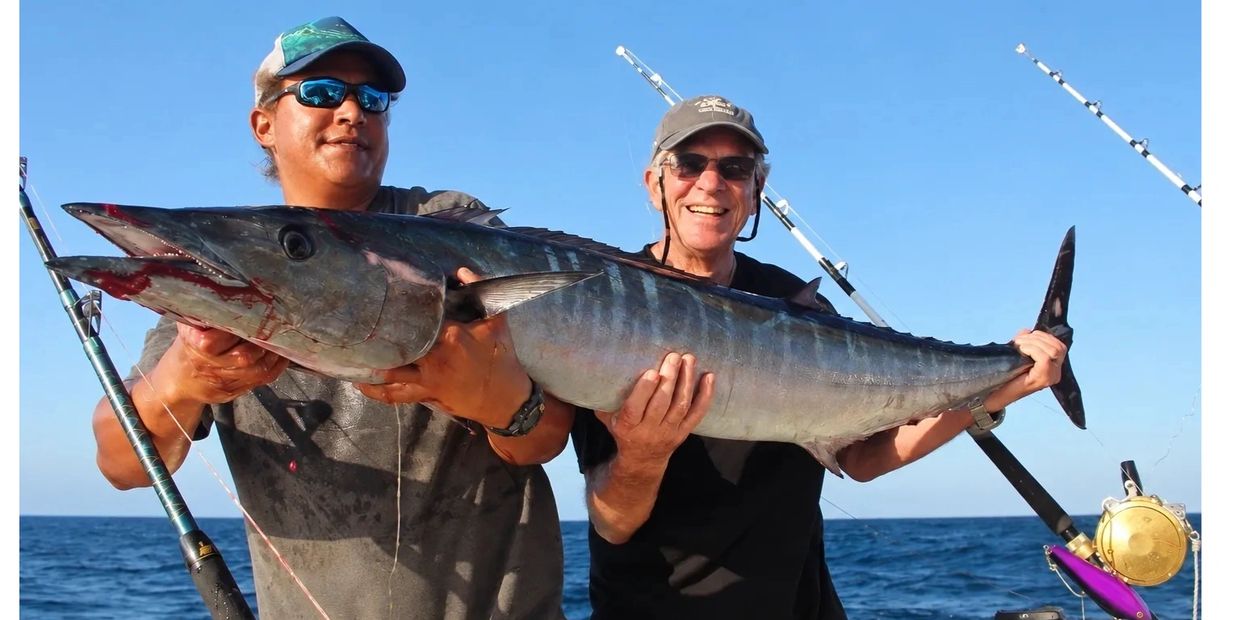 Two men holding a large fish on a boat.