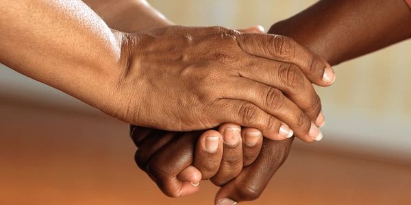 Two hands holding each other in a gesture of support and care.
