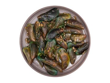 Plate of cooked green mussels with garlic and herbs.