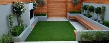 Modern small backyard with green lawn, wooden fence, and built-in seating area.