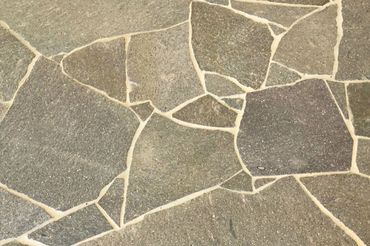 Irregular stone pavement with light-colored grout.