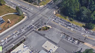 Aerial view of a busy intersection with multiple lanes and cars waiting at traffic lights.
