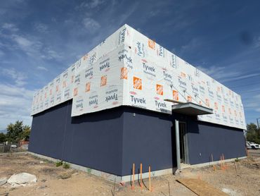 Building under construction with Tyvek wrap and dark blue painted lower walls.