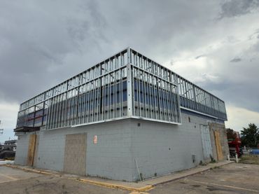 Building under construction with metal framing on top and cloudy sky.