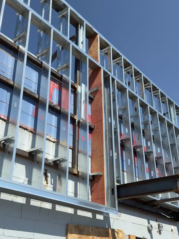Metal framing structure under construction against a clear blue sky.