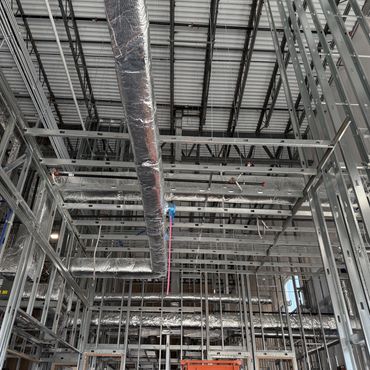 Exposed metal framework and insulated ductwork in a building under construction.